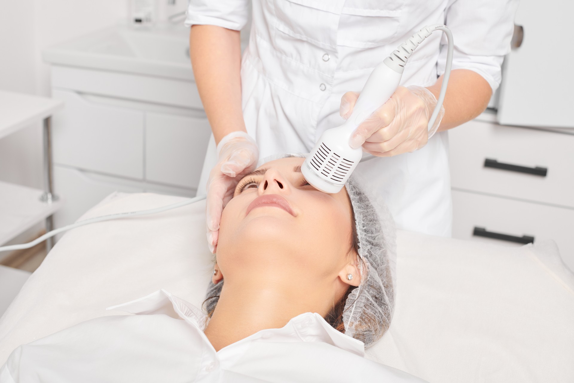 Beautician makes cryotherapy for rejuvenation woman face, anti aging procedure in salon