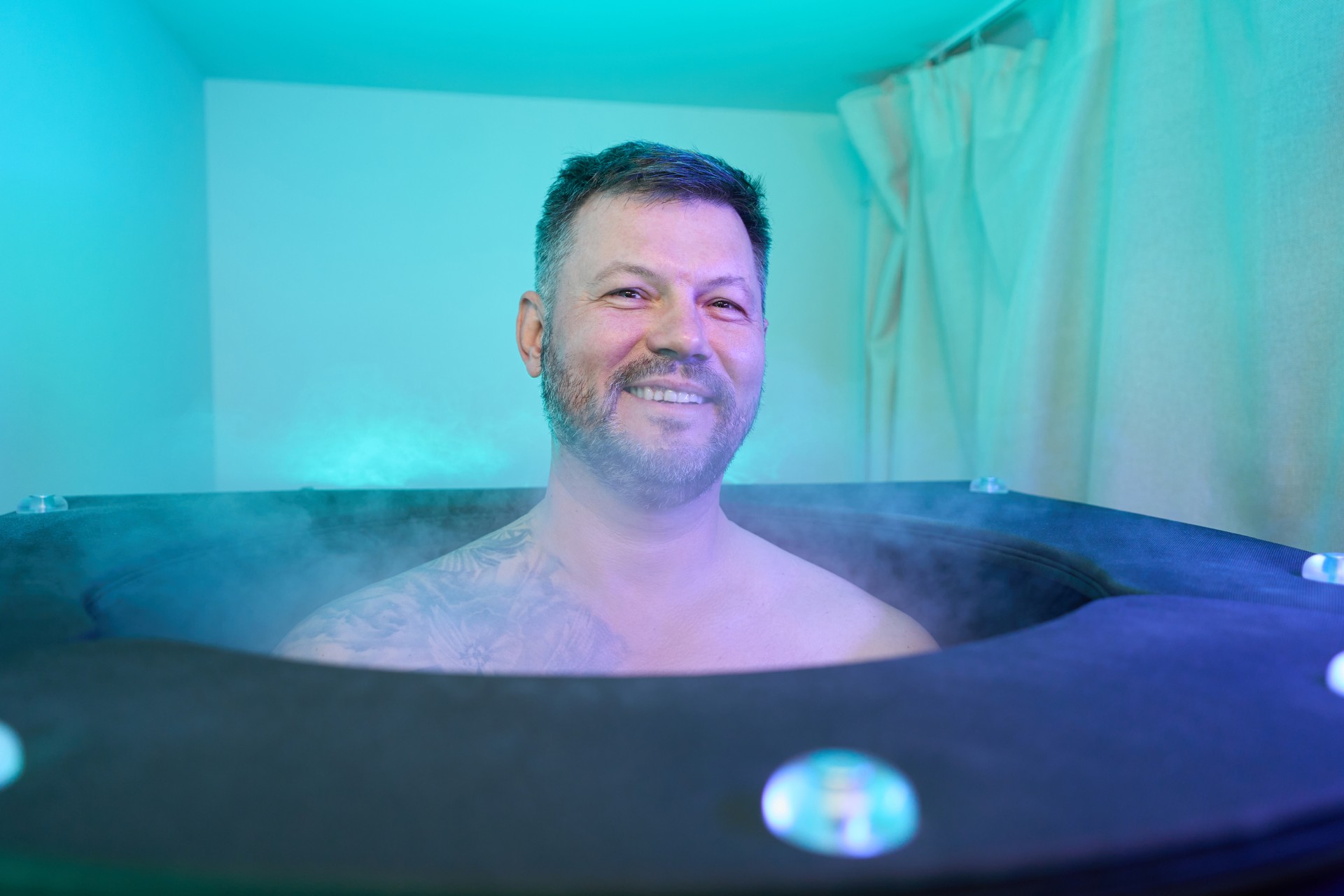 Joyful adult spa client sitting in cryobarrel cabin in wellness center